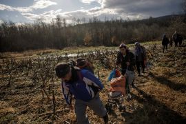A baby is pushed in a stroller as members of a migrant family from Afghanistan approach Croatia's border from Bosnian side