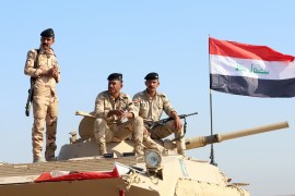 Iraqi army officers sit on a military vehicle.