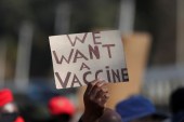 A person holds a placard during a protest demanding a rollout of coronavirus disease (COVID-19) vaccines, in Pretoria, South Africa June 25, 2021 [Siphiwe Sibeko/Reuters]