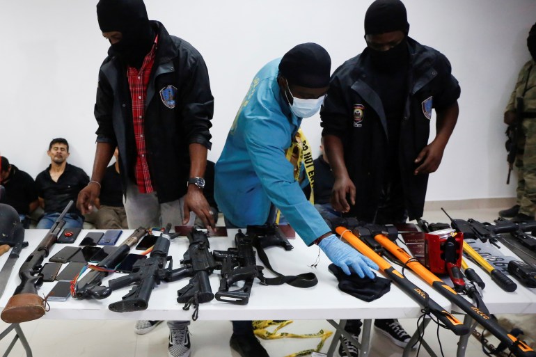 Weaponry, mobile phones, passports and other items are being shown to the media along with suspects in the assassination of President Moise, who was shot dead early on Wednesday at his home in the Haitian capital, Port-au-Prince [Estailove St-Val/Reuters]