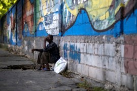 A man sits on a sidewalk in Port-au-Prince after Jovenel Moise's assassination