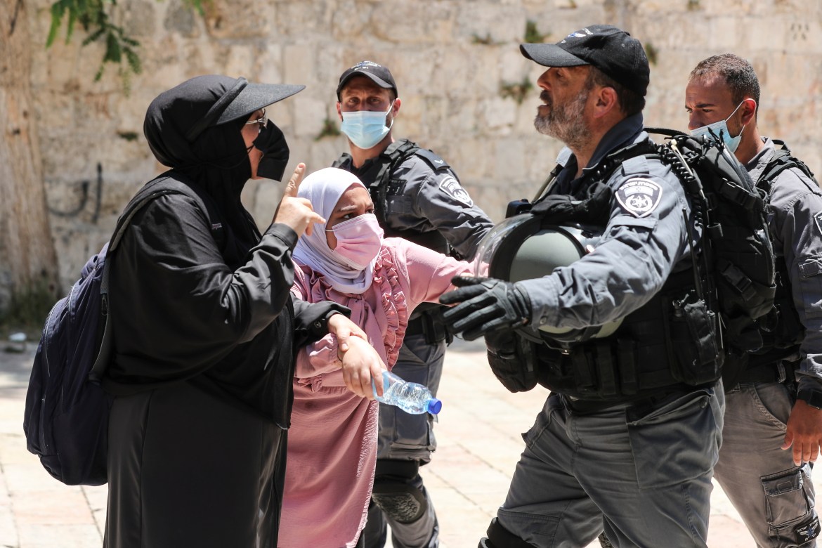 Palestinian women argue with an Israeli security force member at Al-Aqsa Mosque over visits by Jews on the Tisha B'Av fast day. [Ammar Awad/Reuters]