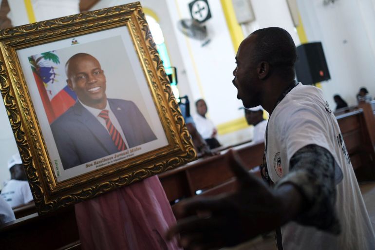 A man prays in front of a picture of slain Haitian President Jovenel Moise