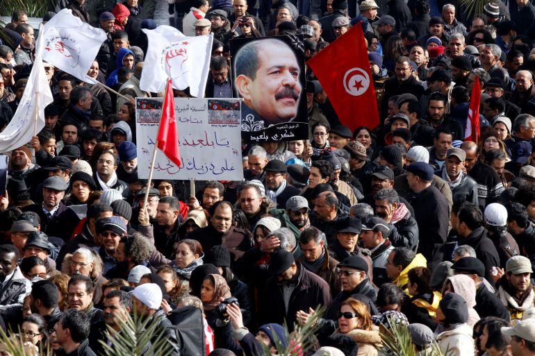 unisians hold a placard with an image of the late secular opposition leader Chokri Belaid during his funeral procession in the Jebel Jelloud district in Tunis