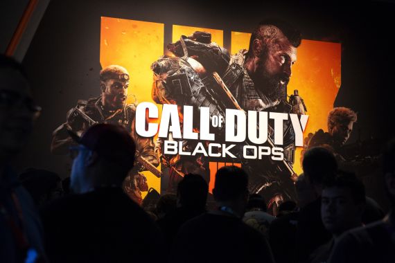 Attendees stand next to signage for Activision Blizzard Inc. Call Of Duty: Black Ops 4 video game during the E3 Electronic Entertainment Expo in Los Angeles, California, US