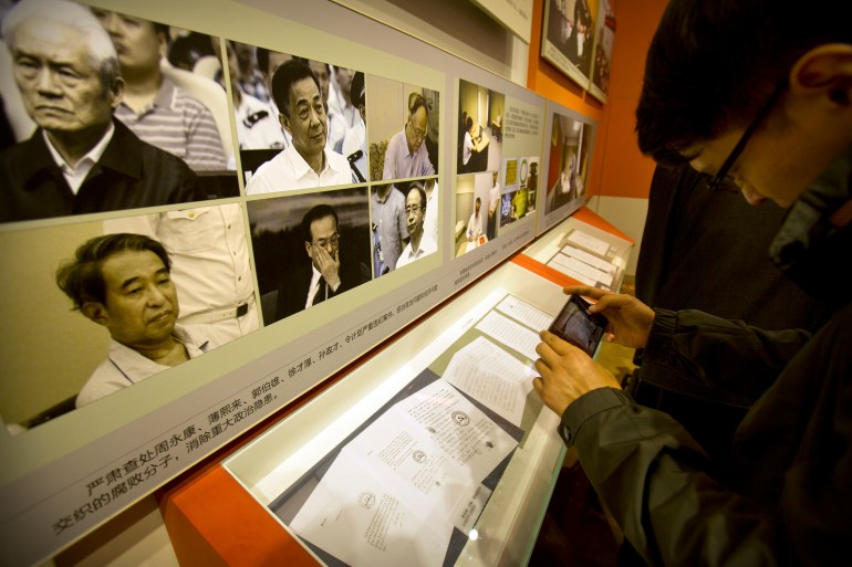 A man takes a photo of a display showing Chinese leaders who have been convicted of various crimes at an exhibition highlighting China's achievements under five years of leadership by Chinese President Xi Jinping at the Beijing Exhibition Hall in Beijing, Thursday, September 28, 2017 [File: Mark Schiefelbein/AP]
