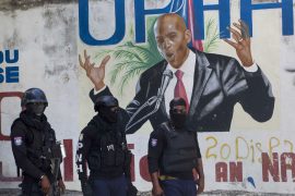 Police stand in front of a mural depicting slain Haitian President Jovenel Moise