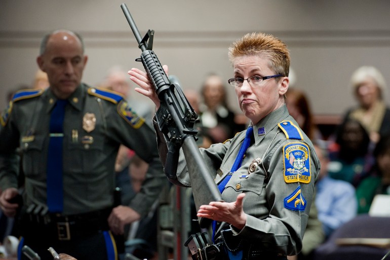 Connecticut State Police Detective Barbara Mattson holds up a Bushmaster AR-15 rifle, the same make and model of gun used by Adam Lanza in the Sandy Hook School shooting