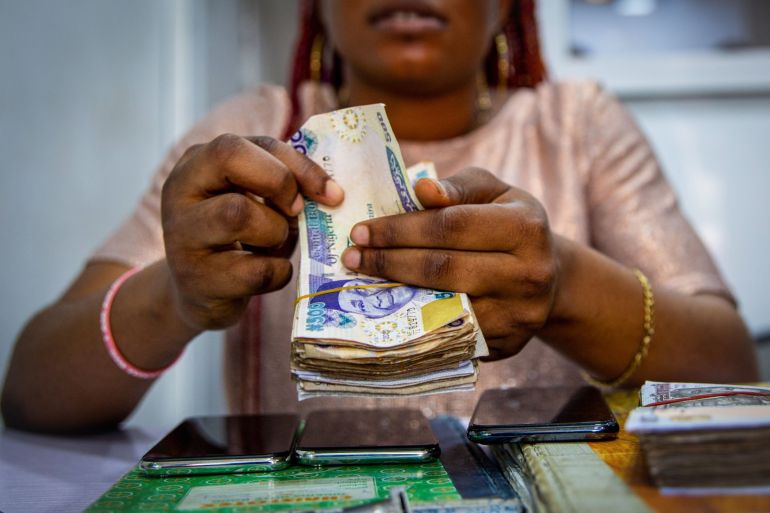 A vendor counts out Nigerian naira banknotes inside a shop at the Ikeja computer village market in Lagos, Nigeria