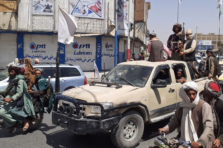 Taliban fighters drive an Afghan National Army vehicle through a street in the southern city of Kandahar after its capture [AFP]
