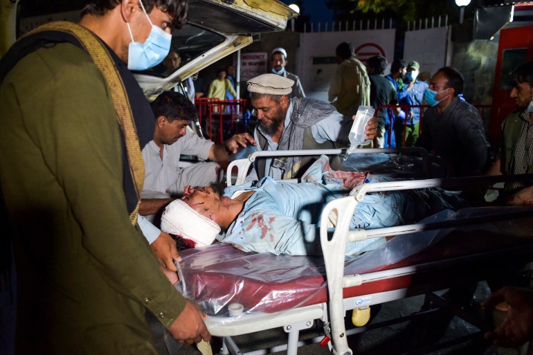 Medical and hospital staff bring an injured man on a stretcher for treatment after two blasts, which killed at least five and wounded a dozen, outside the airport in Kabul on August 26, 2021 [Wakil Kohsar/AFP]