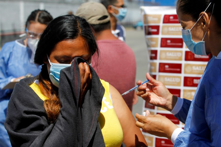 A migrating woman receives a coronavirus vaccine at the US-Mexico border