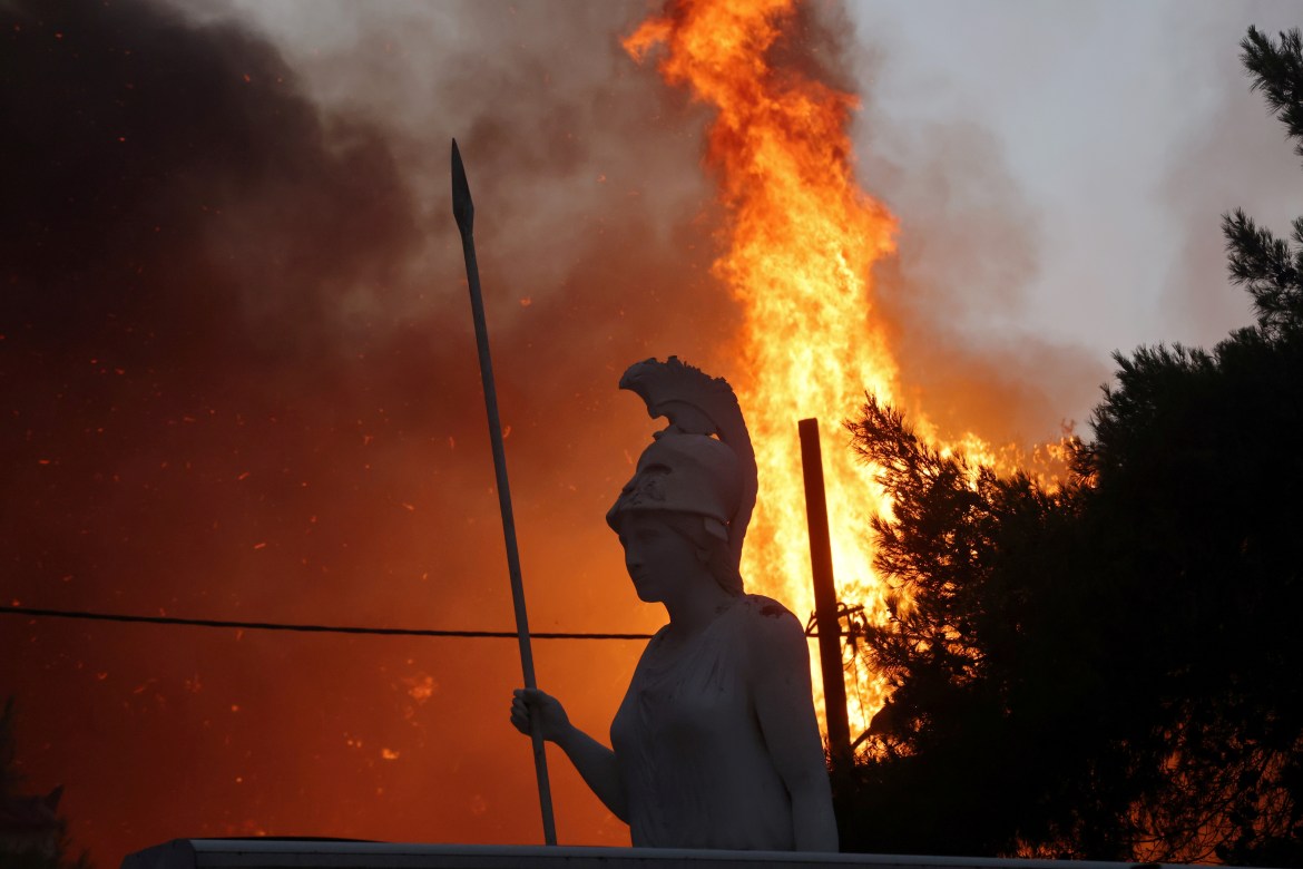A statue of goddess Athena is seen as wildfire burns at Varympompi, a northeastern suburb of Athens. [Giorgos Moutafis/Reuters]