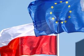 The Polish flag waves behind the EU flag.