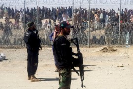 Pakistani soldiers stand guard in front of people waiting to cross at the Friendship Gate crossing point in the Pakistan-Afghanistan border town of Chaman, Pakistan [Abdul Khaliq Achakzai/Reuters]