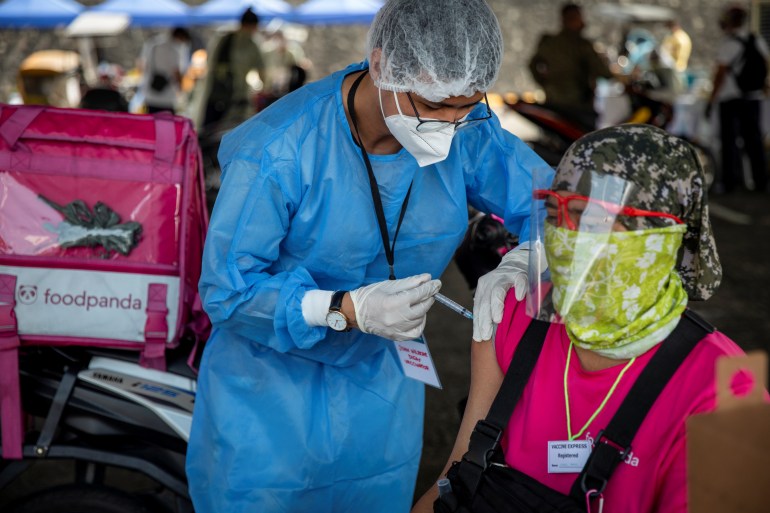 A health worker vaccinates a foodpanda delivery rider with Sinovac COVID-19 vaccine