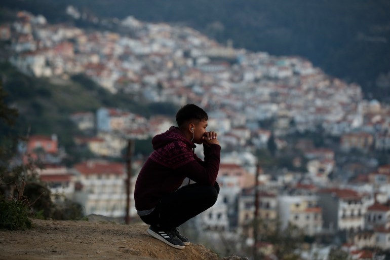 A migrant sits on a hill outside a refugee camp on the eastern Aegean island of Samos, Greece.