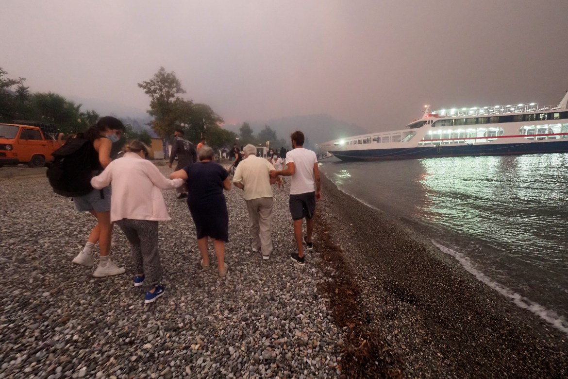 People walk towards a ferry during an evacuation from Kochyli Beach. Greece has requested help through the EU's emergency support system. [Thodoris Nikolaou/AP Photo]