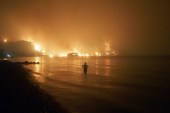 A man watches the flames as a wildfire approaches Kochyli beach near Limni village on the island of Evia in Greece on August 6, 2021 [Thodoris Nikolaou/AP]