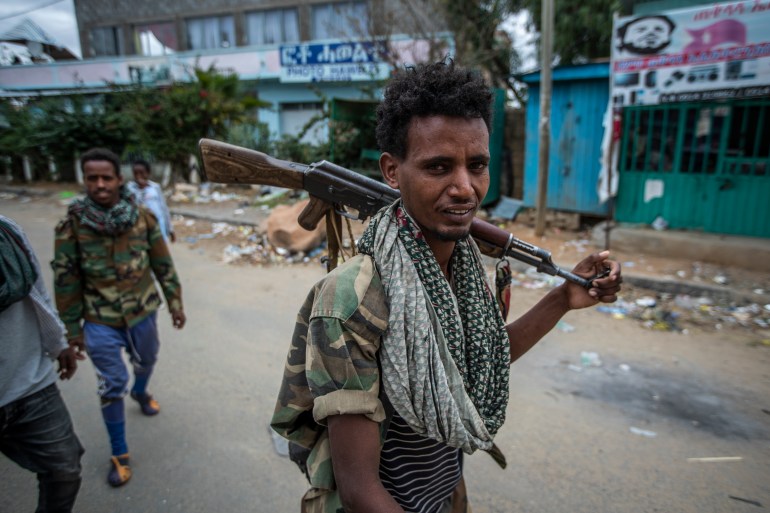 Fighters loyal to the Tigray People's Liberation Front (TPLF) walk along a street in the town of Hawzen [File: Ben Curtis/AP]