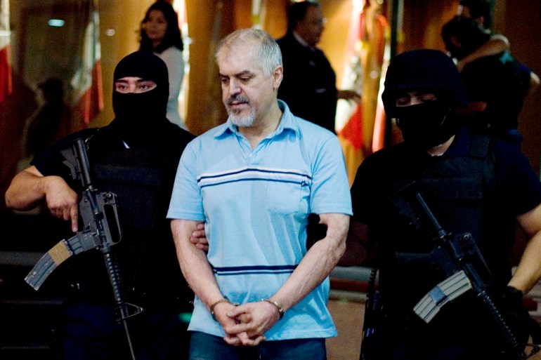 Eduardo Arellano Felix, also known as 'The Doctor', centre, is escorted by masked police officers during his presentation to the press in Mexico City in 2008 [File: Alexandre Meneghini/AP Photo]