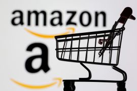 Small toy shopping cart is seen in front of displayed Amazon logo in this illustration, taken July 30, 2021.