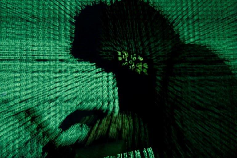 A man is seen holding a laptop computer as cyber code is projected on him