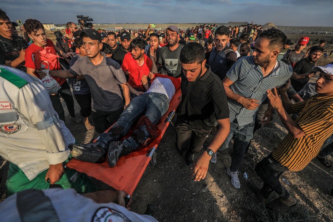Palestinian protesters carry a wounded young man. Forty-one Palestinians and one Israeli soldier were injured during the fighting near the boundary east of Gaza City. [Mohammed Saber/EPA