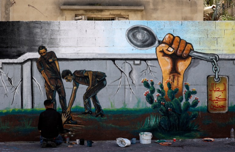 An creator  works   connected  a mural coating  glorifying six Palestinian prisoners who escaped from Israel's Gilboa situation  successful  September 2021 with the assistance   of the humble spoon [Mahmud Hams/AFP]