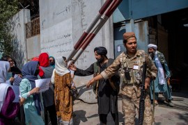 Afghan women converse with a Taliban fighter while they hold placards during a demonstration demanding better rights for women in front of the former Ministry of Women Affairs in Kabul on September 19, 2021