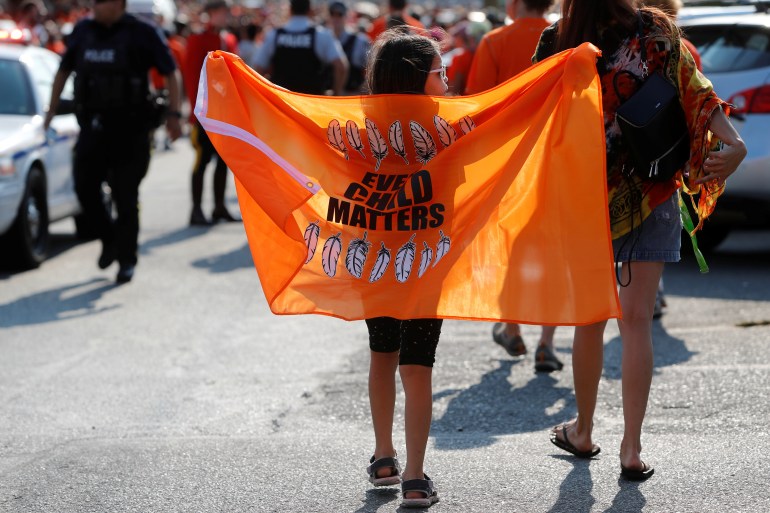 A child holds an orange flag that reads, Every child matters