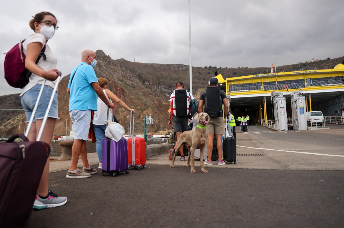 Tourists wait for the ferry to leave the island after La Palma Airport was closed, suspending flights because of the accumulation of ash following the eruption. [Nacho Doce/Reuters]
