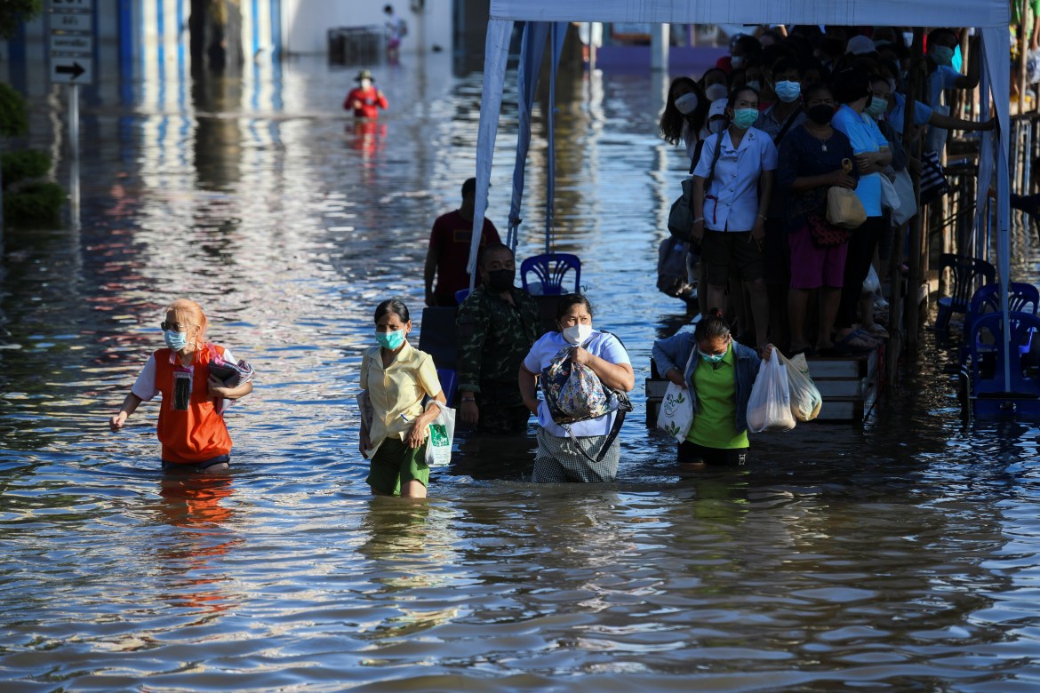 People wade through a flooded street in Chaiyaphum. Seven people have died and two are missing since Sunday from flooding triggered by Tropical Storm Dianmu, the Department of Disaster Prevention and Mitigations said. [Panumas Sanguanwong/Reuters]