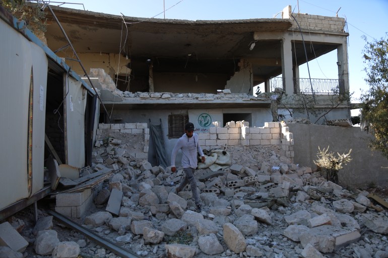 A man walks near the ruins of a medical point south of Idlib. The building has two floors. 