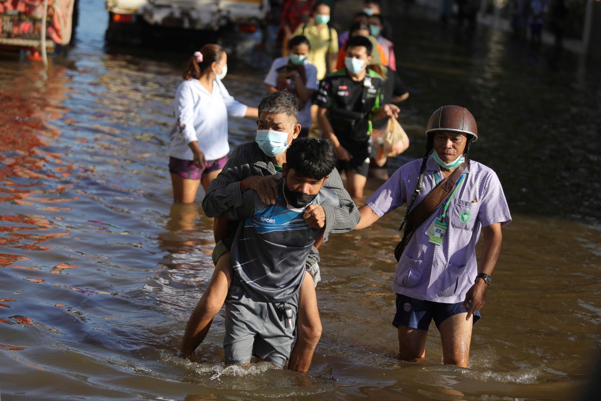 People wade through floodwaters in Chaiyaphum. The capital Bangkok and other parts of central Thailand have received new warnings of possible major flooding. [Nava Sangthong/AP Photo]