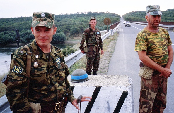 A Russian peacekeeping officer (left), a Moldavian soldier (centre) and a Transnistrian solder (right) stand on guard in the security zone, next to the Dniester River. [File: Yoray Liberman/Getty Images]