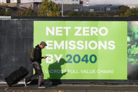 A man walks past an advertisement near the venue for the UN Climate Change Conference (COP 26) in Glasgow, Scotland on October 30, 2021 [Reuters/Yves Herman]