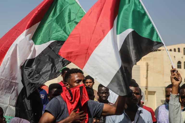 Sudanese protesters hold national flag and chant during a demonstration in the capital Khartoum, Sudan, on 25 October 2021 [Mohammed Abu Obaid/EPA-EFE]