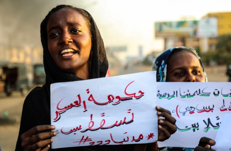 Sudanese female protesters hold placards reading, 'Military government down'