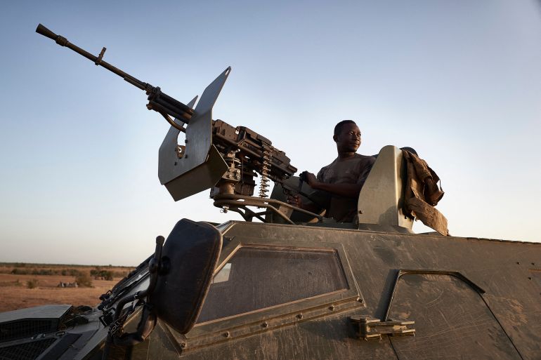 A soldier of the Burkina Faso Army poses on the top of an armoured vehicle during a patrol in the Soum region in northern Burkina Faso on November 12, 2019. (Photo by MICHELE CATTANI / AFP)