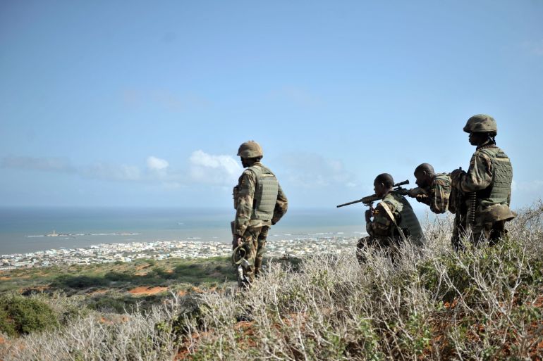 Soldiers belonging to the African Union Mission in Somalia looking through the scope of a sniper for enemy fighters on a hill overlooking the al-Shabab stronghold of Barawe, Somalia, in October 2014