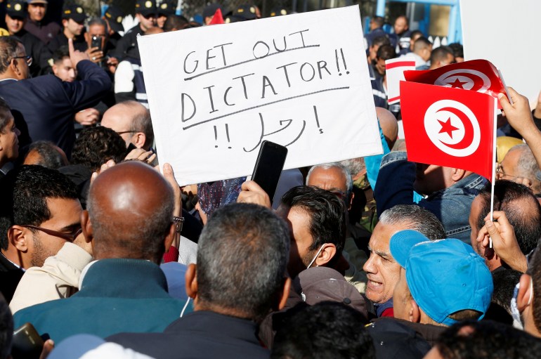 Protesters are seen with a placard that reads 'get out dictator' in Tunis, Tunisia.