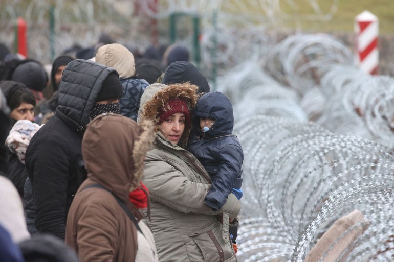 Migrants and refugees gather near a fence on the Belarusian-Polish border