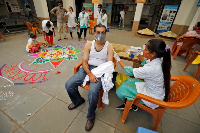 A healthcare worker gives a dose of vaccine to a man in India