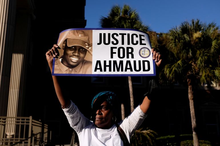 A woman holds a sign that reads, 'Justice for Ahmaud'