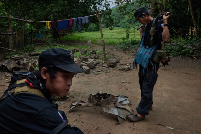 KNPF (Karen National Police Force) officers inspect the remains of a bomb which was dropped on Dae Pu Noh village in March during a Tatmadaw airstrike. [Al Jazeera] - DO NOT USE
