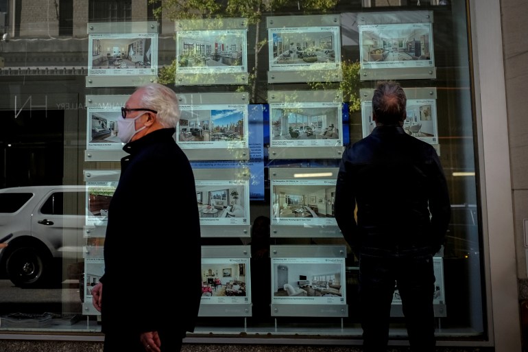 A man looks at advertisements for luxury apartments and homes in the window of a Douglas Elliman Real Estate sales business in Manhattan's upper east side neighborhood in New York City, New York, U.S