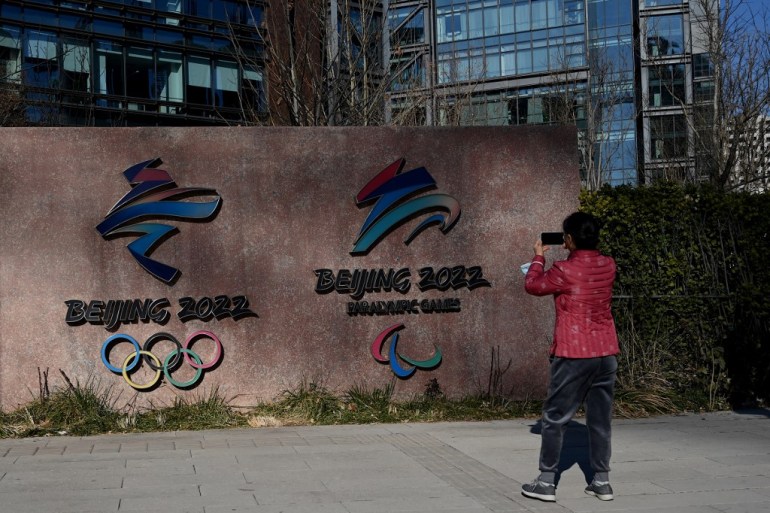 A woman takes a photo of the logos of Beijing 2022 Winter Olympics and Paralympic Winter Games in Shougang Park, one of the sites for the Olympics