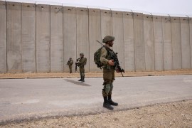Israeli soldiers stand along the border fence with Gaza