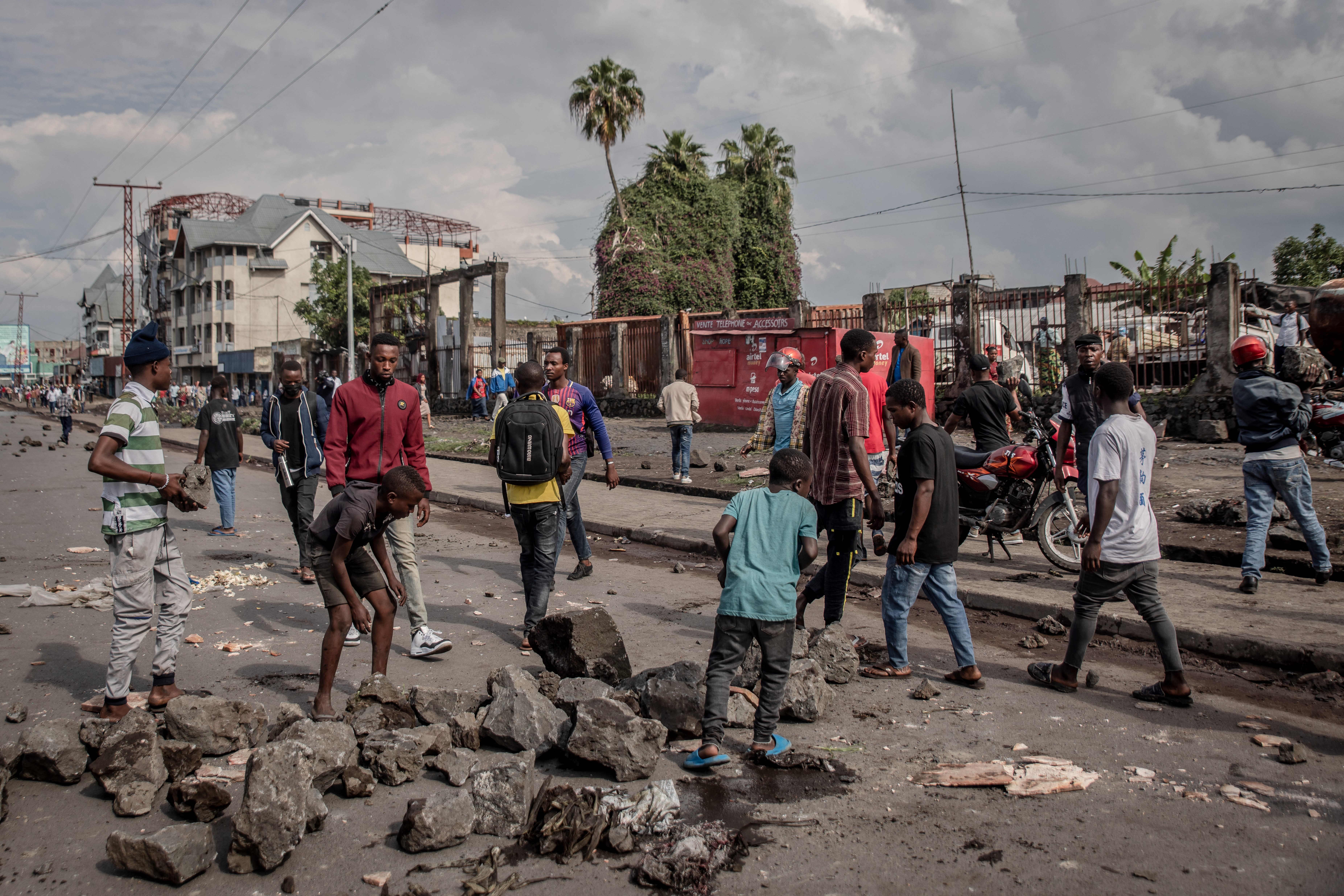 Pessoas removem pedras de uma rua enquanto a polícia dispersa pessoas bloqueando estradas em Goma, leste da República Democrática do Congo, em 20 de dezembro de 2021.
